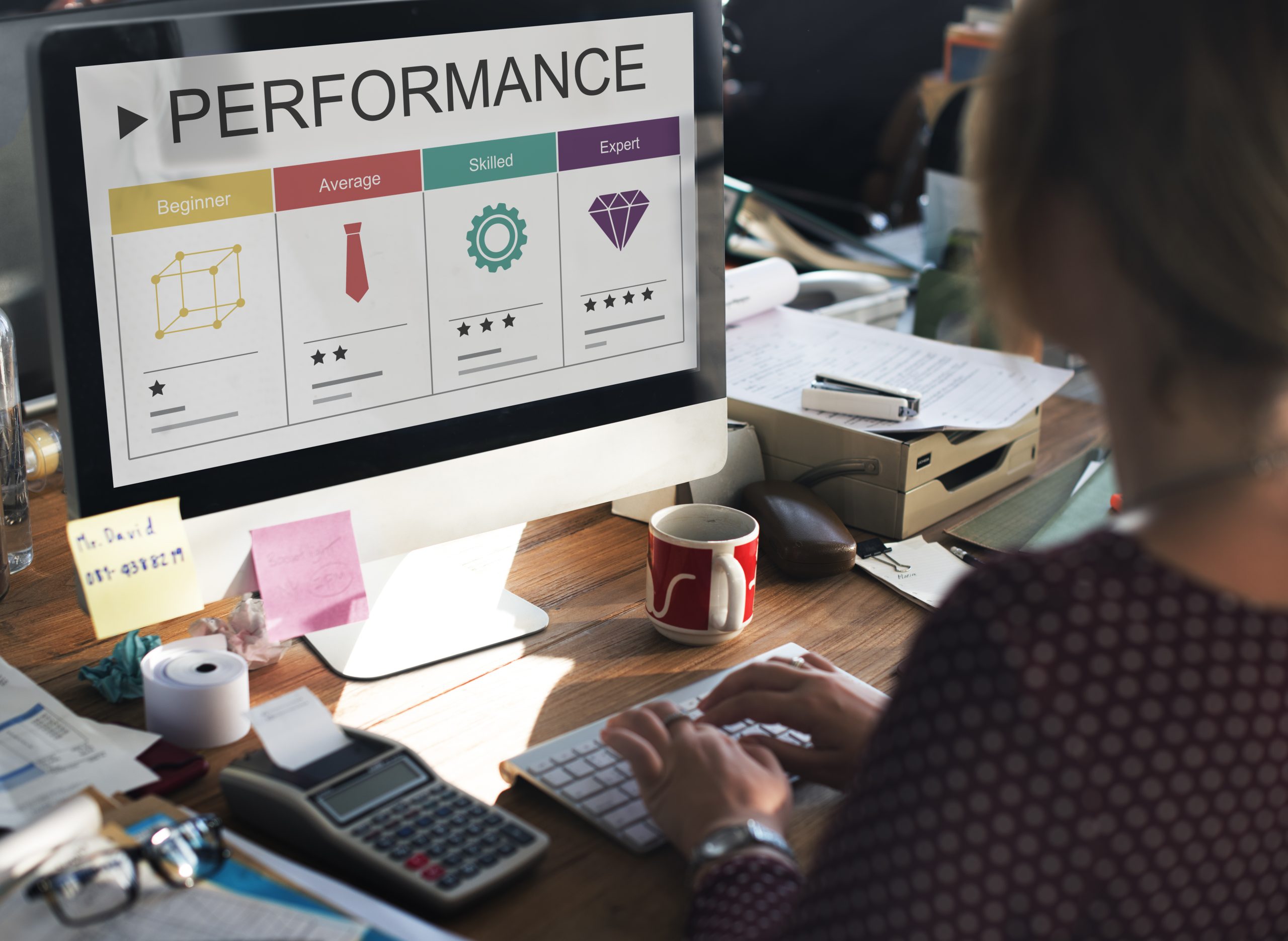 Professional working at a desktop computer displaying a performance management dashboard with employee skill level metrics labeled Beginner, Average, Skilled, and Expert, representing OKR implementation, workforce performance tracking, and HR analytics in the UAE.