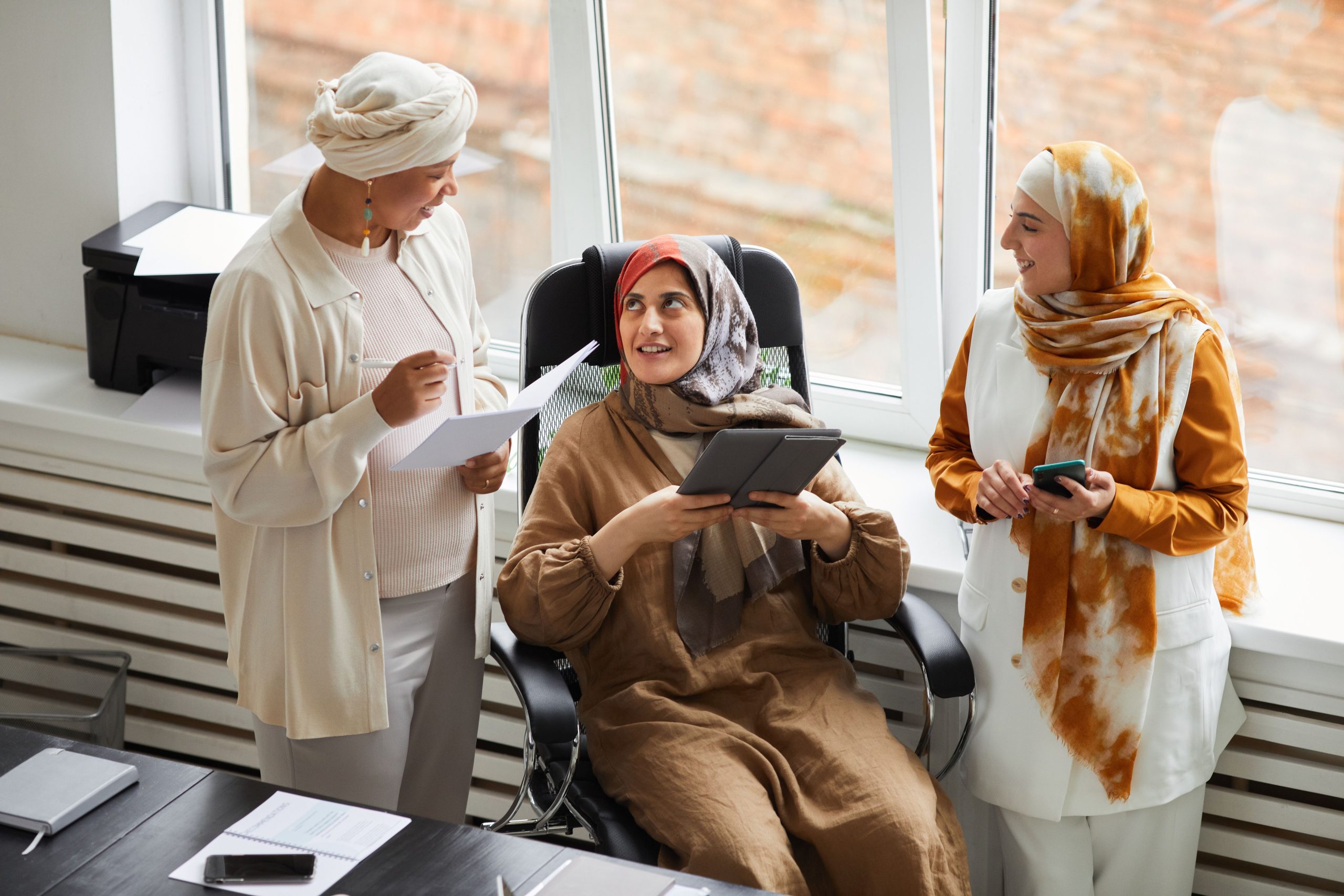Digital marketing services team reviewing strategy documents and performance updates using a tablet and smartphone during a business meeting