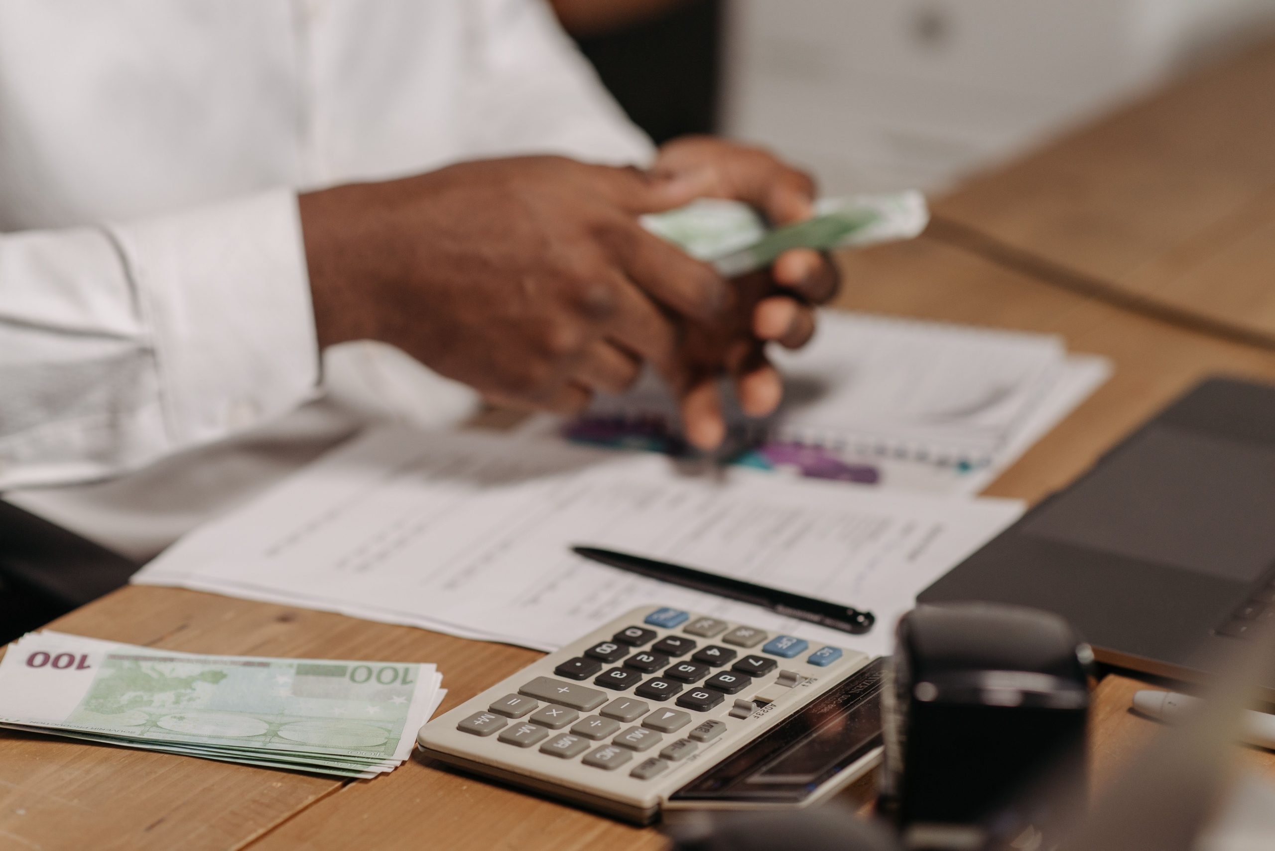 Payroll management services in UAE professional calculating payments with cash, documents, and calculator for accurate payroll processing.
