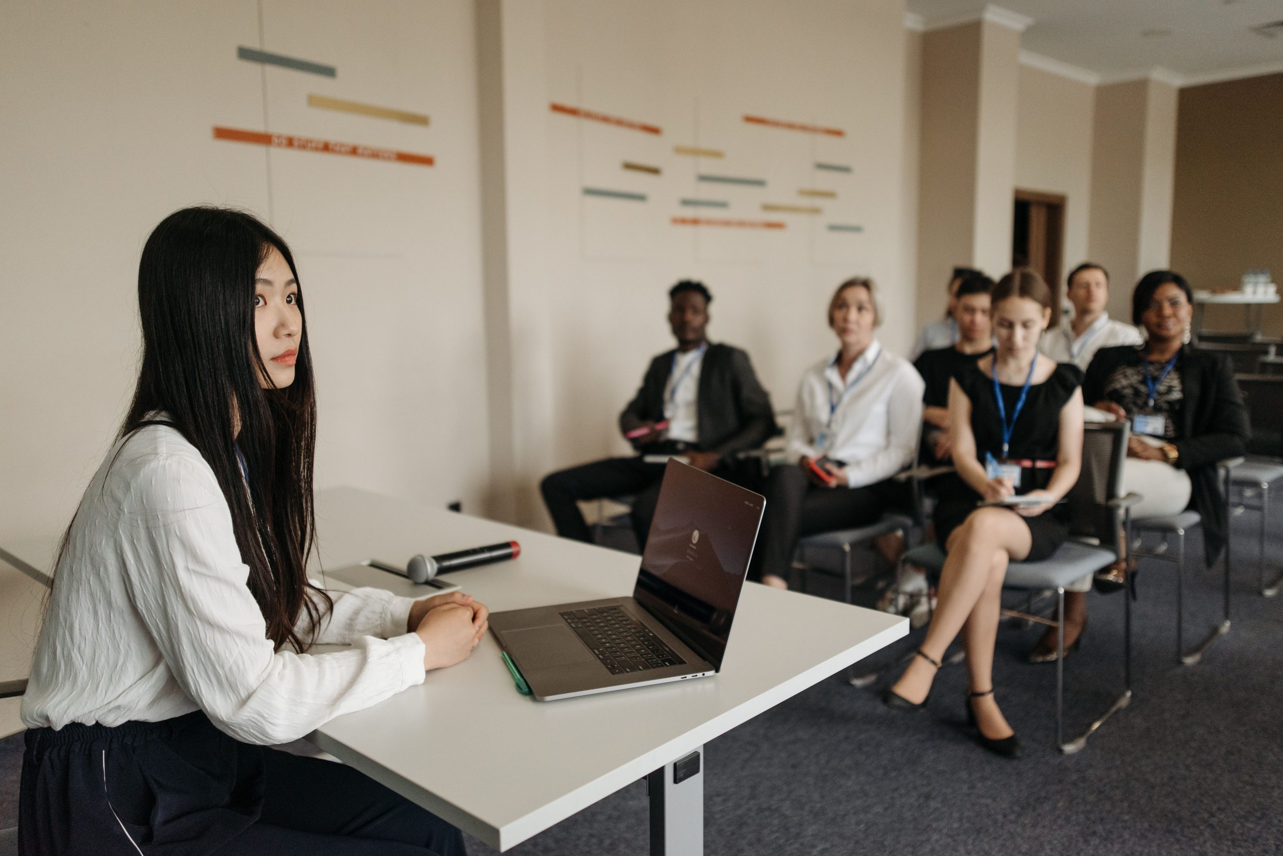 Woman leading a training session in front of employees with laptops in a classroom setting, supporting Performance Management Consulting UAE initiatives.
