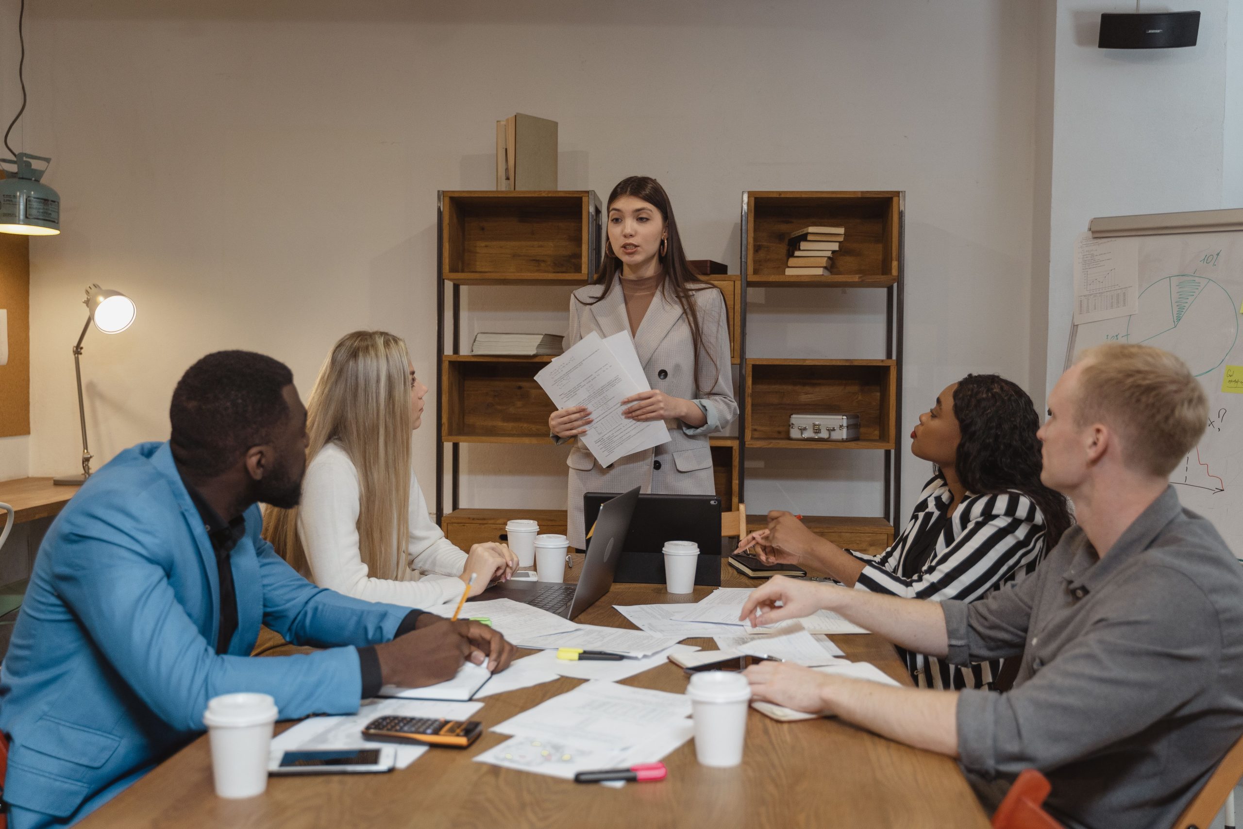 HR Outsourcing Services in UAE team meeting with a female consultant holding documents and leading a business discussion