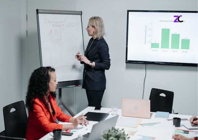 Women explaining the difference between OKRs and KPIs to UAE employees in a conference room.