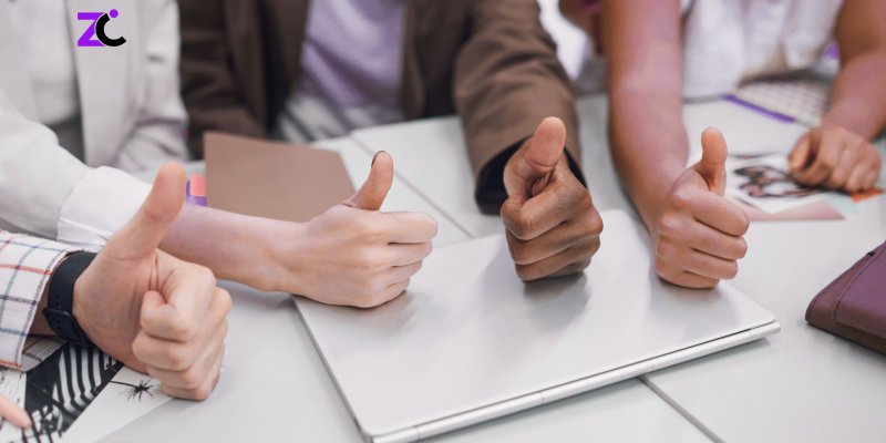 "A diverse group of employees in a UAE office giving thumbs up, representing employee satisfaction, competitive compensation and benefits, talent retention, and HR consulting services in the UAE."