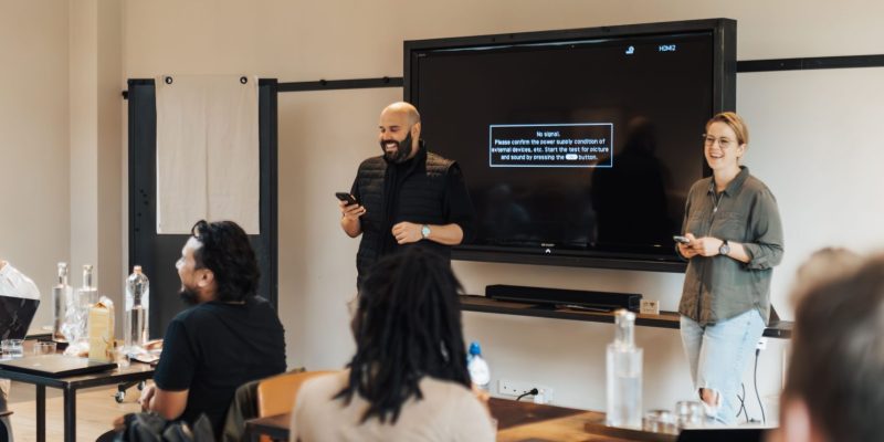 Male trainer conducting a training session while a professional team listens, representing Sales Training & Coaching Services, employee development, sales coaching, and team learning.