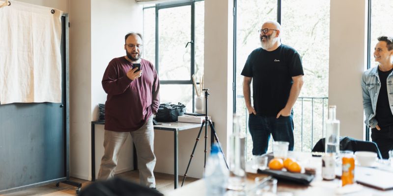 Two coaches standing together while listening to employees during a team coaching session.