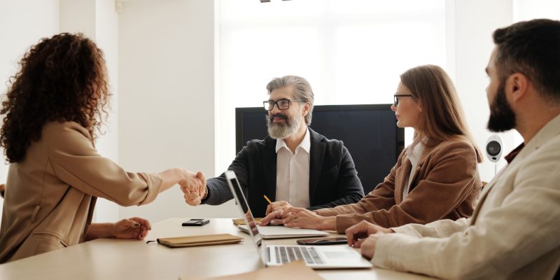 Recruitment Services in UAE interview with one man and two women meeting a candidate while the hiring manager shakes hands after a successful interview.