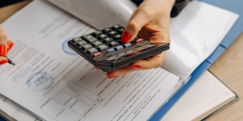 Payroll management services in UAE professional reviewing documents and calculating payroll details with a calculator.