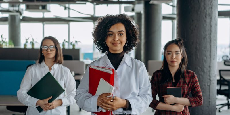 Human Capital Consulting Services featuring three confident business professionals standing together with files in hand.